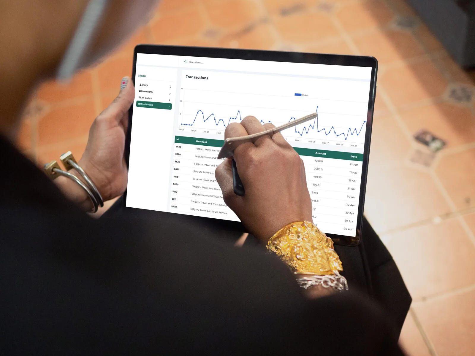 Hands holding a tablet showing the Mocard transactions dashboard and chart